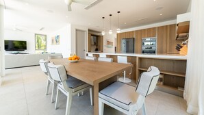 Une cuisine moderne avec une table à manger en bois, des chaises blanches et un four encastré.