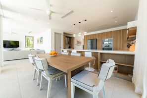 Eine moderne Küche mit einem Holztisch, weißen Stühlen und einem eingebauten Backofen.