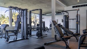 Une salle de sport équipée de divers appareils d’exercice, notamment des machines de musculation et des bancs.