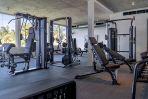 Une salle de sport équipée de divers appareils d’exercice, notamment des machines de musculation et des bancs.