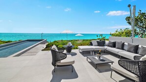 Une terrasse sur le toit avec une piscine, des espaces de détente en plein air et une vue sur l’océan.