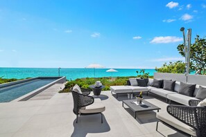 Una terraza en la azotea con piscina, mobiliario exterior y vistas al océano.