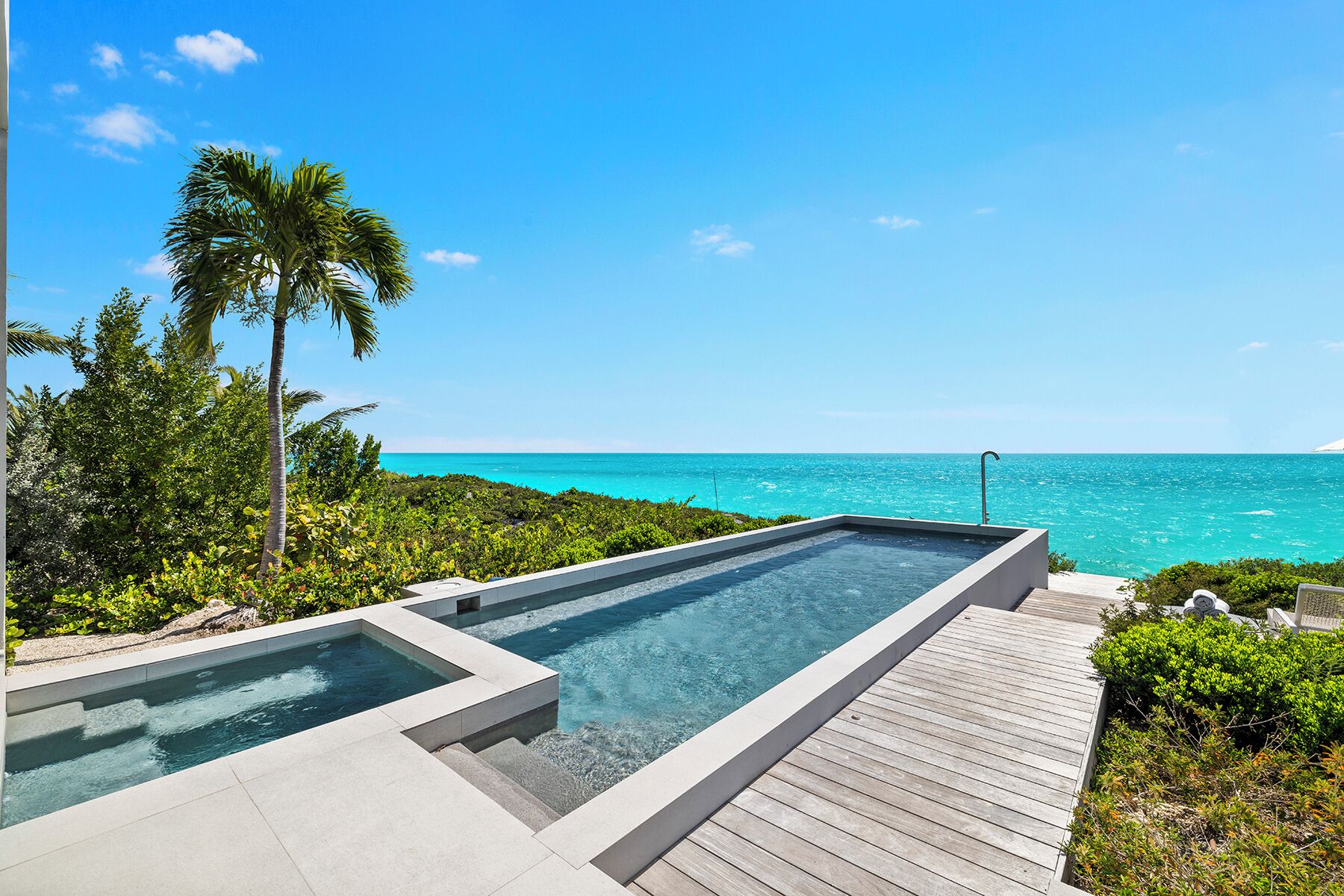 A swimming pool with a wooden deck and a view of the ocean.