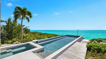 A swimming pool with a wooden deck and a view of the ocean.