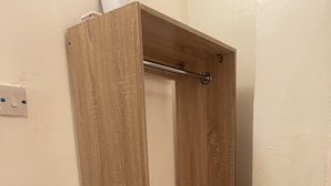 Une armoire en bois avec une tringle en métal et une étagère.