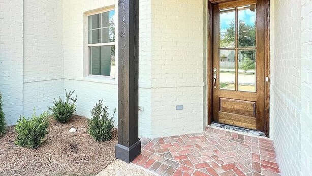 A house exterior with a white brick facade, a wooden door, and a window.
