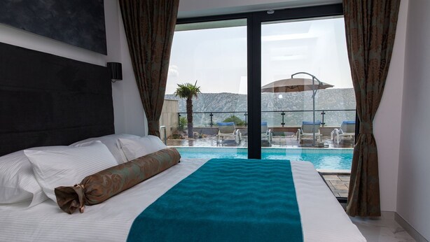 A hotel room with a bed, a view of a swimming pool, and a mountain in the background. - Luxury villa with private pool, sea view (Blaškovici)