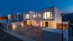 A modern multi-story residential building with a courtyard, large windows, and outdoor lighting. - Luxury villa with private pool, sea view (Blaškovici)