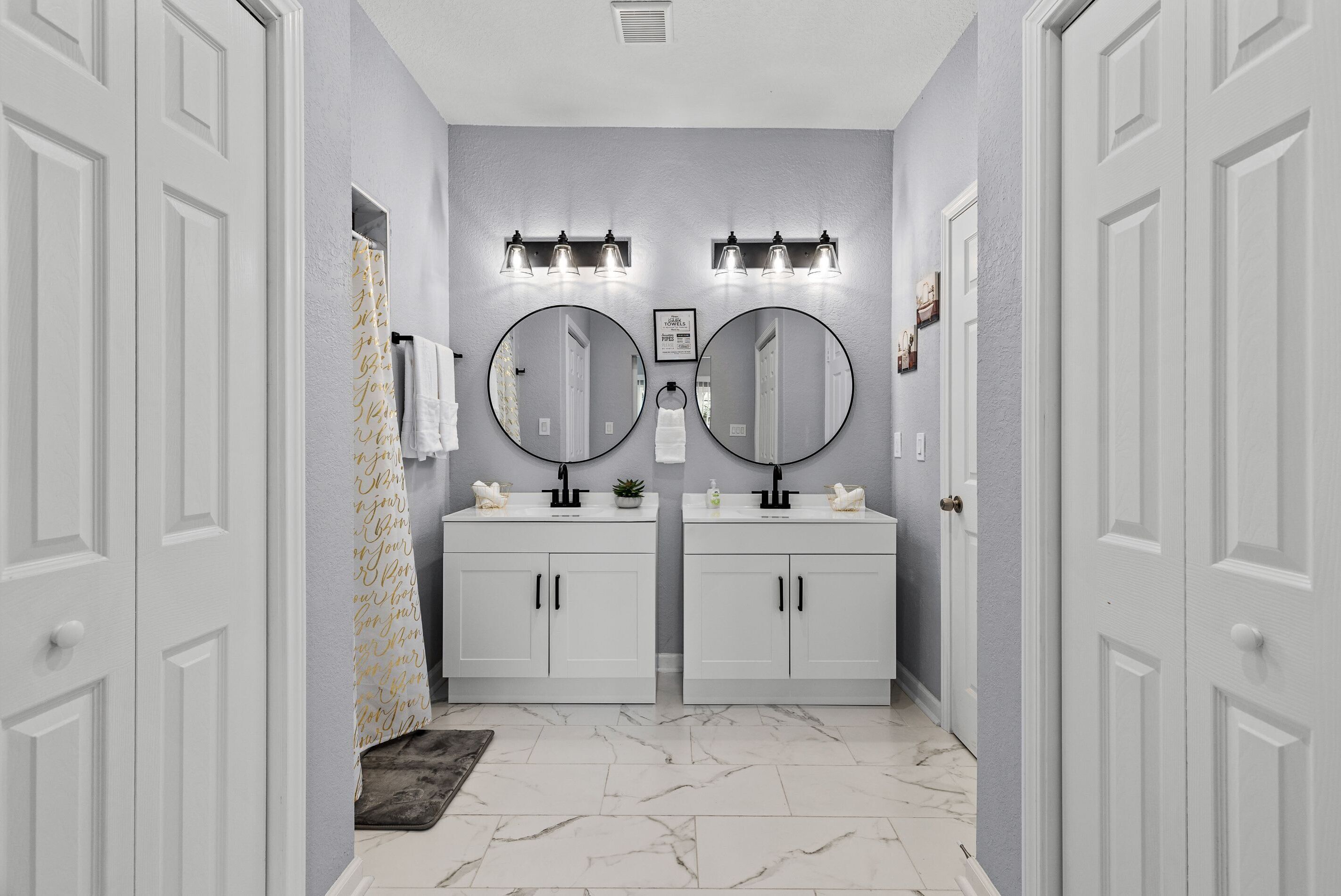 A bathroom with two sinks, a mirror, and a shower curtain.