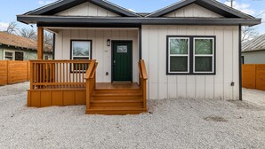 A single-story house with a front porch, a green door, and a number '718' above the door.