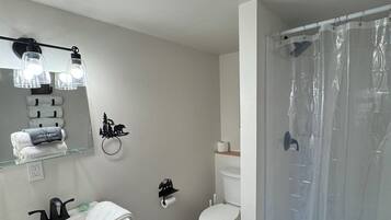 A bathroom with a white sink, toilet, and shower area.