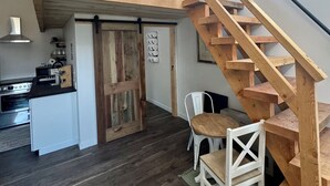 Un espace de vie de style loft avec un escalier en bois, un coin cuisine et un espace repas.