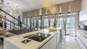A modern kitchen with a central island, large windows, and a view of the outdoors.