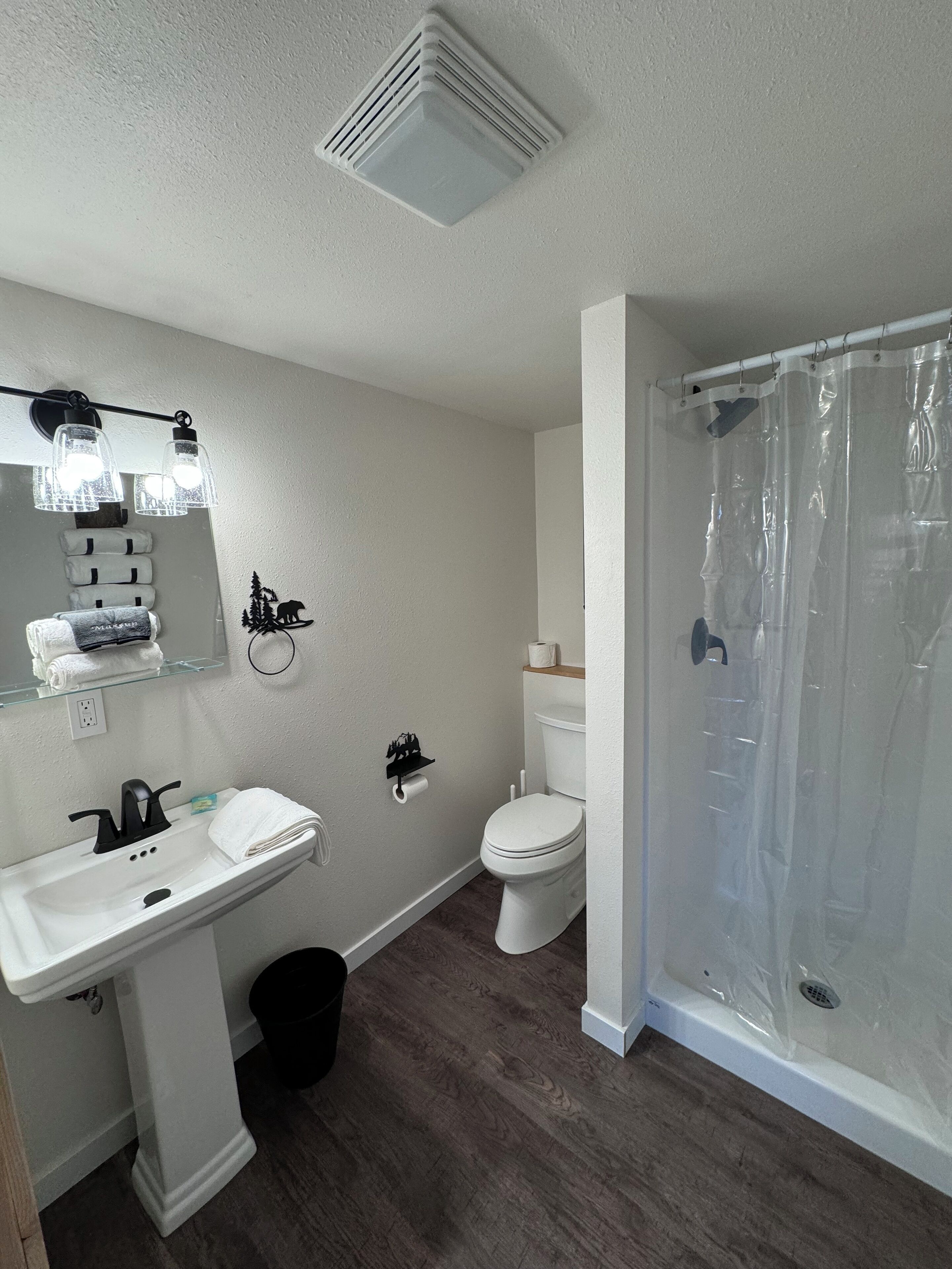 A bathroom with a white sink, toilet, and shower area.
