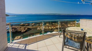A balcony with a clear view of the sea and boats, a tiled floor, and a table with a glass. - Directly by the sea (Selce)