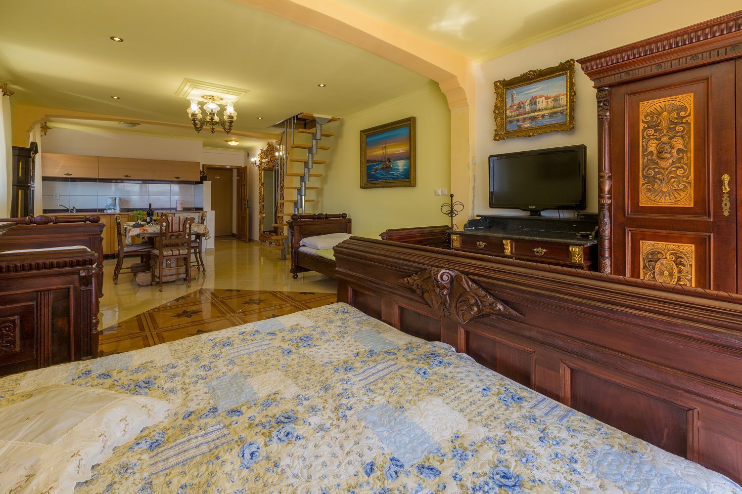Un dormitorio amplio con una cama grande, televisión y cómoda de madera.