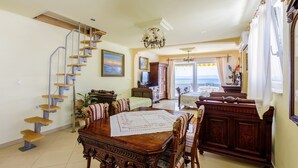 A dining area with a wooden table, chairs, and a staircase with metal railings. - Directly by the sea (Selce)