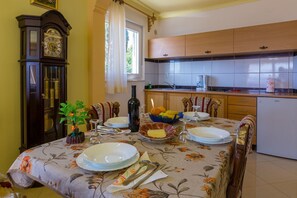 Enjoy meals in this cozy dining area with a table set for four, featuring a floral tablecloth and a vintage clock on the wall.