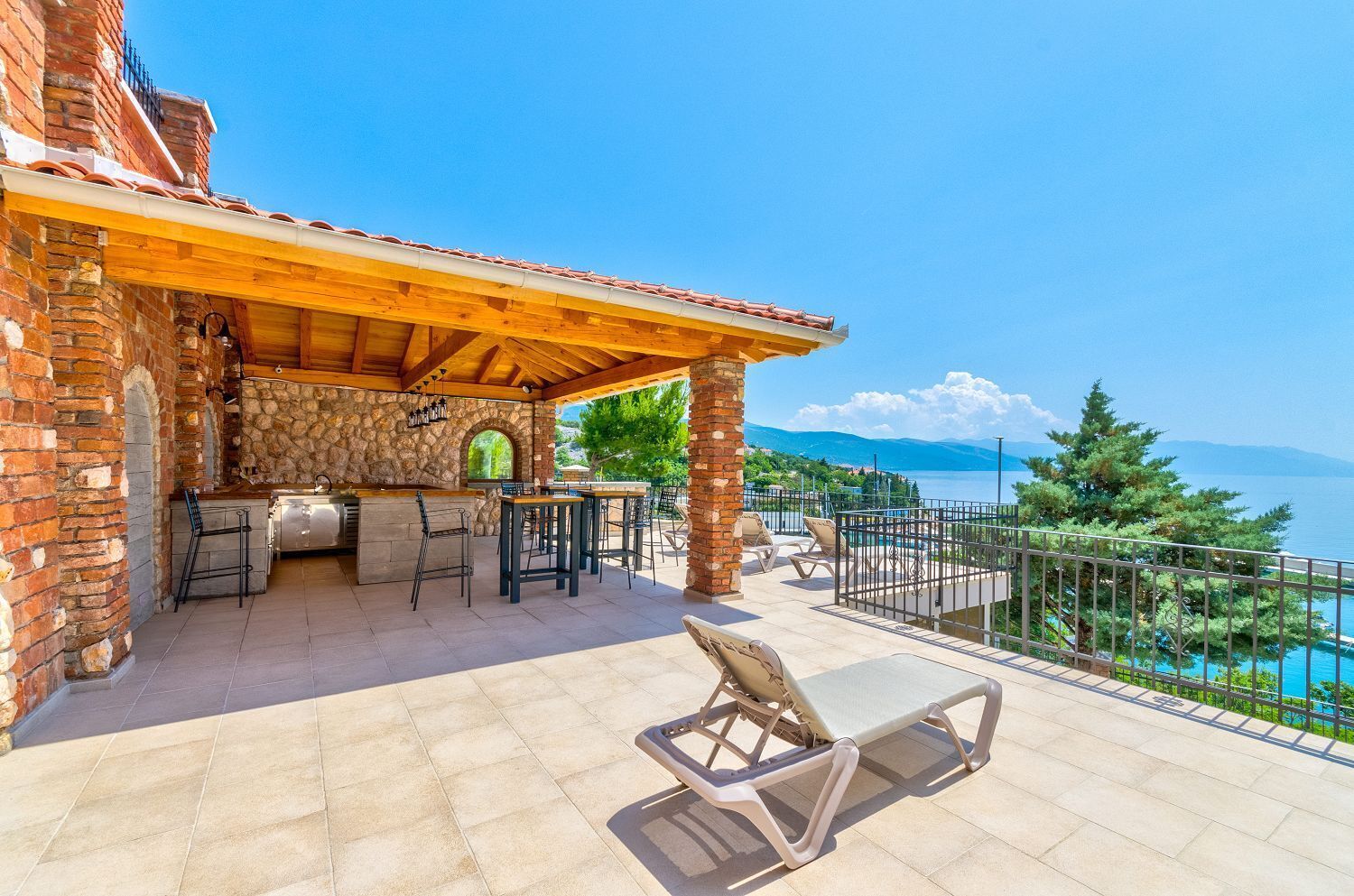 A patio with a stone fireplace, outdoor seating, and a view of a lake.
