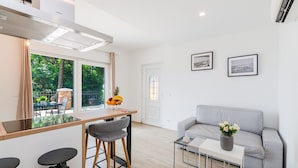 A modern kitchen with a dining area, a grey sofa, and a small table with a vase of flowers. - Luxury with pool, sauna, whirlpool directly by the sea (Novi Vinodolski)