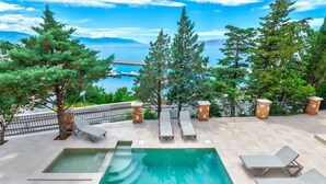 A pool area with lounge chairs and a view of the sea.