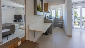 Uma cozinha moderna com forno embutido, área de refeições com mesa e cadeiras, e uma grande janela com vista para o exterior.