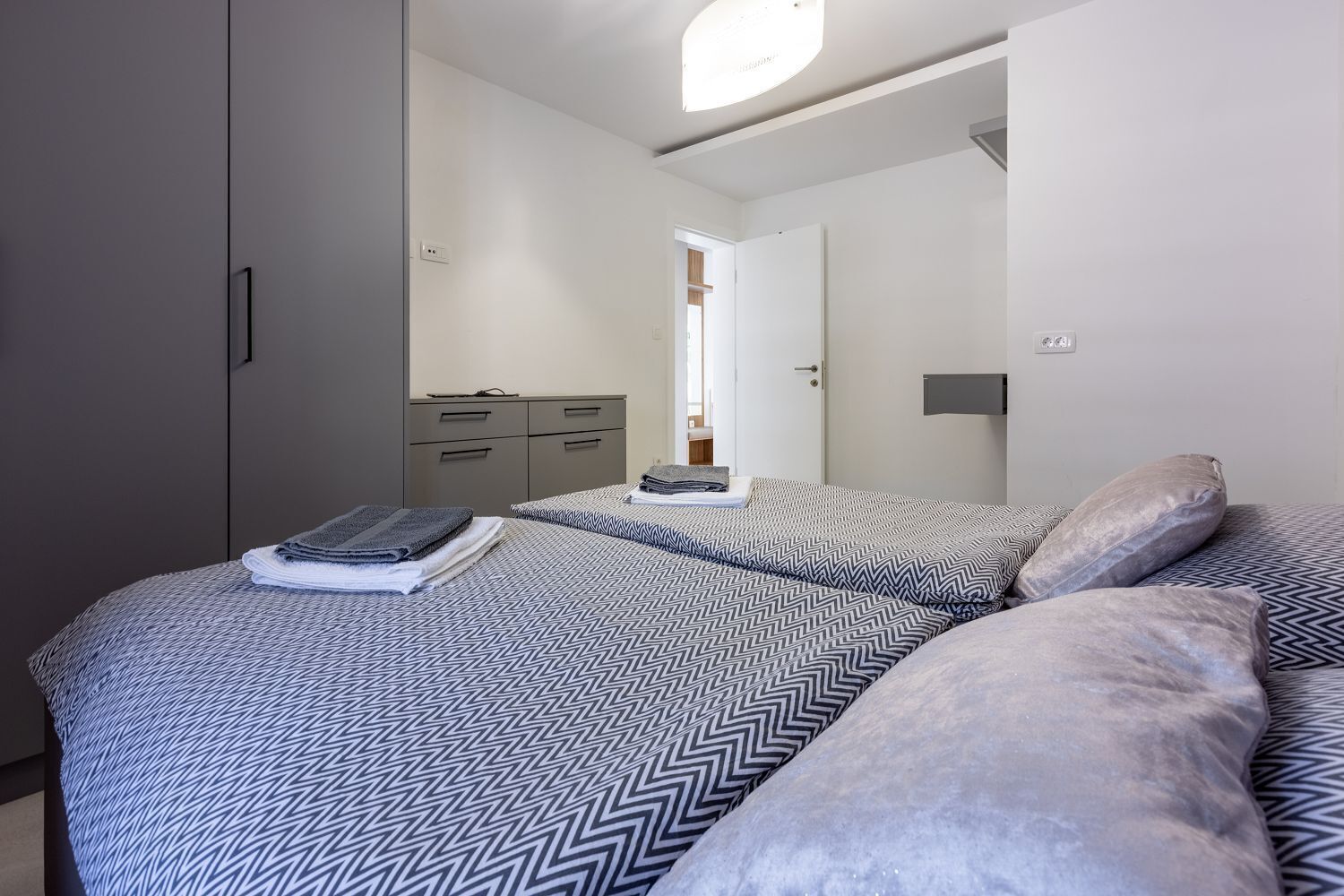 Een slaapkamer met twee bedden, een grijze garderobe en een spiegel.