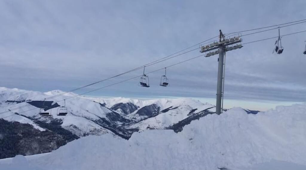 Une montagne enneigée, dotée de remontées mécaniques, sous un ciel dégagé.
