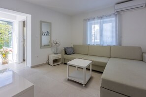 A modern living room with a sofa, a small table, a nightstand, and a mirror.