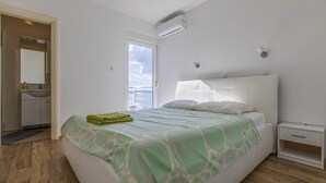 A bedroom with a bed, a nightstand, a window, and a bathroom visible through an open door. - 100 metres beach with sea view (Crikvenica)