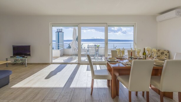 A modern living room with a dining area, large sliding glass doors leading to a balcony with a view of the sea. - 100 metres beach with sea view (Crikvenica)