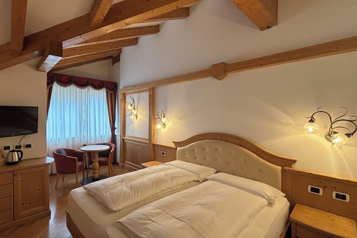 A hotel room with a bed, a television, a desk, and a chair.