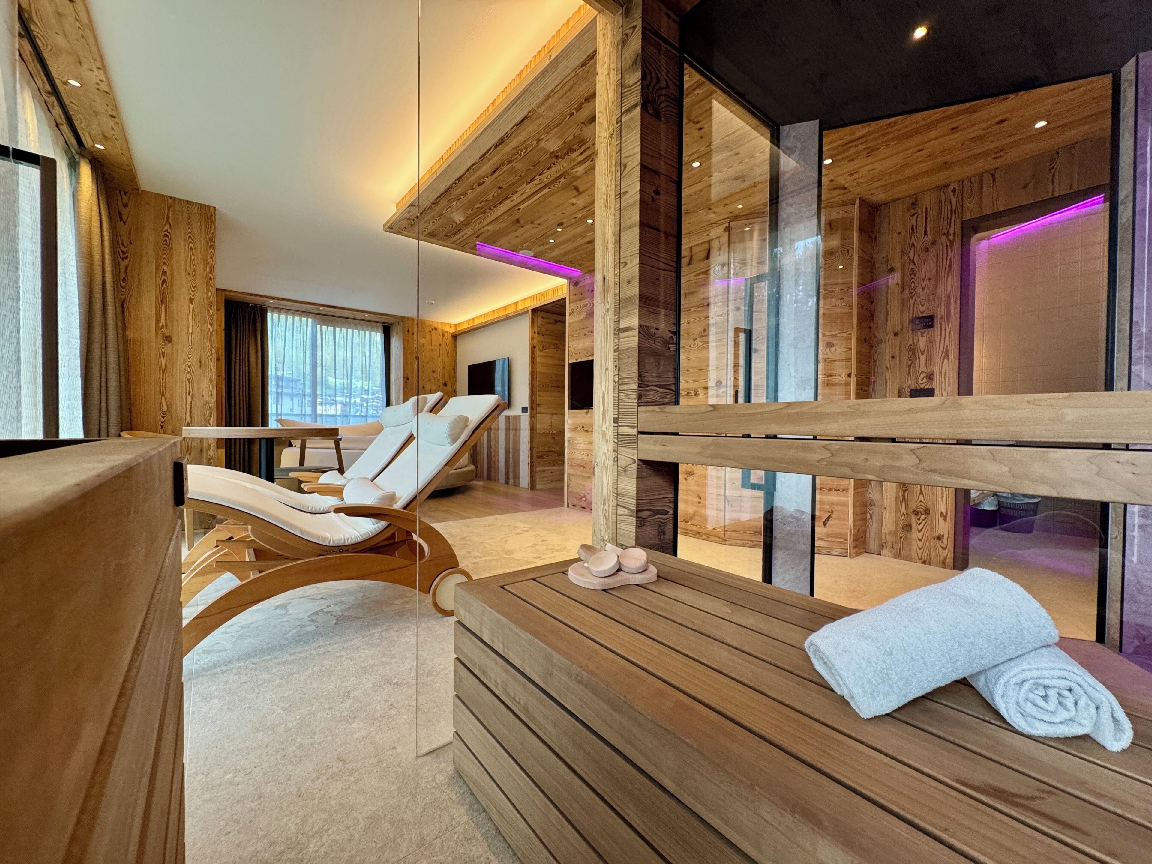 Ein moderner Wellnessraum mit Holzvertäfelung, einer Massageliege, einer Bank und einem Handtuch.