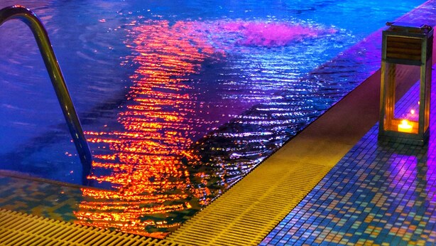 A swimming pool with a waterfall feature, illuminated by colorful lights. - Hotel Mirabello - Slow Hotel Benessere (Fiera di Primiero)