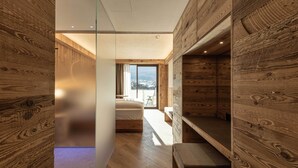 A modern interior with wooden walls, a bed, a bench, and a view of the outdoors. - Hotel Mirabello - Slow Hotel Benessere (Fiera di Primiero)