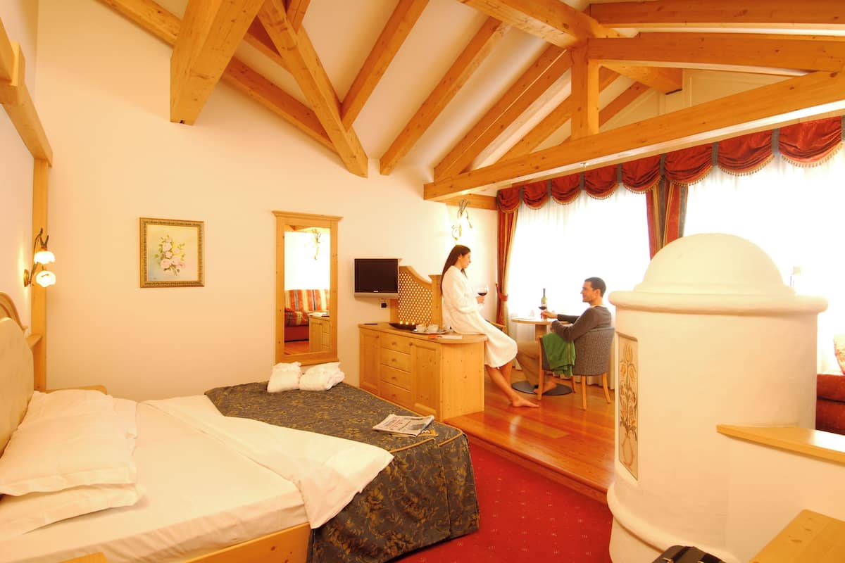 A hotel room with a bed, a desk, a chair, a television, and a large window with curtains.