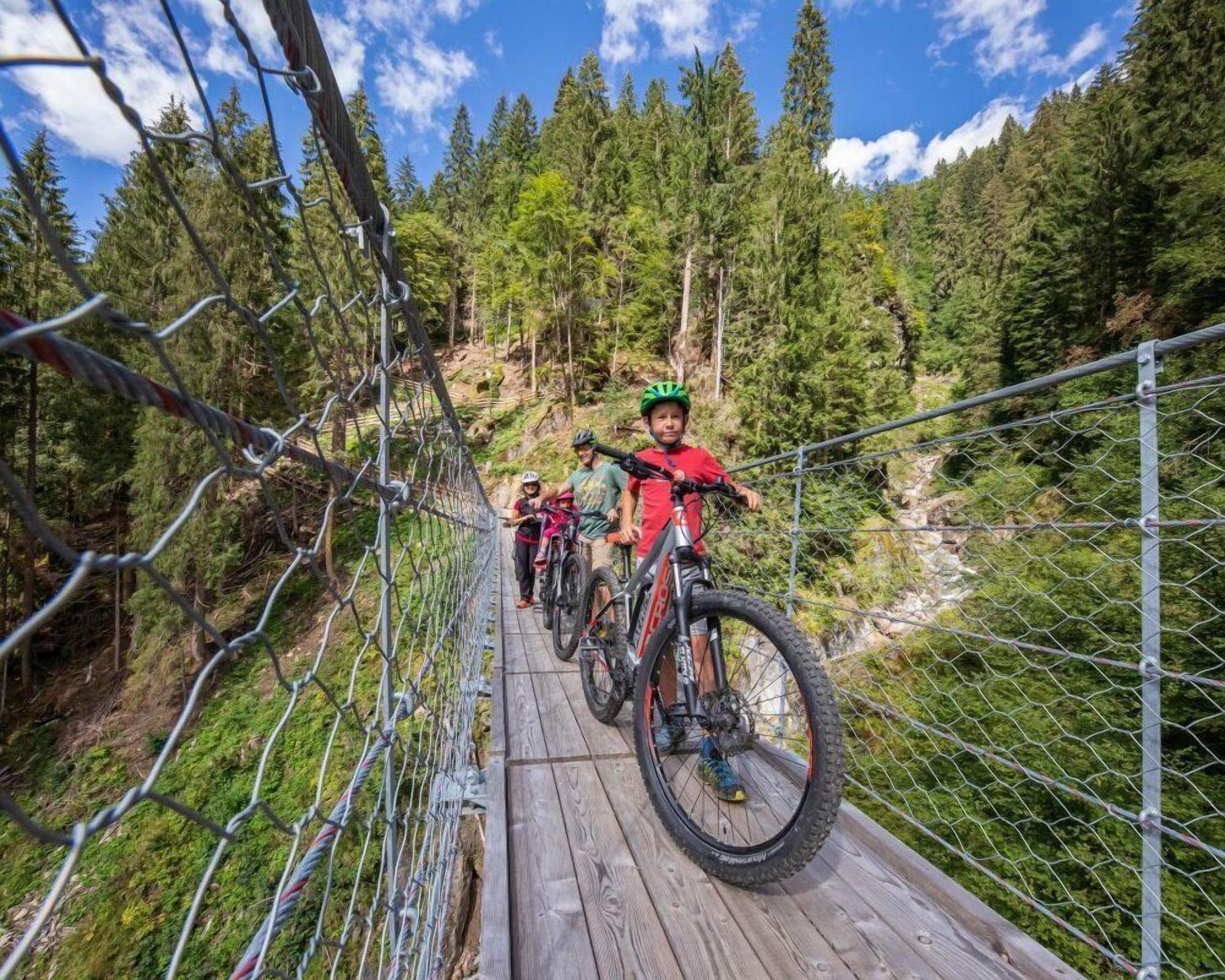 Eine hölzerne Brücke mit Metallgeländern, umgeben von dichtem Wald.