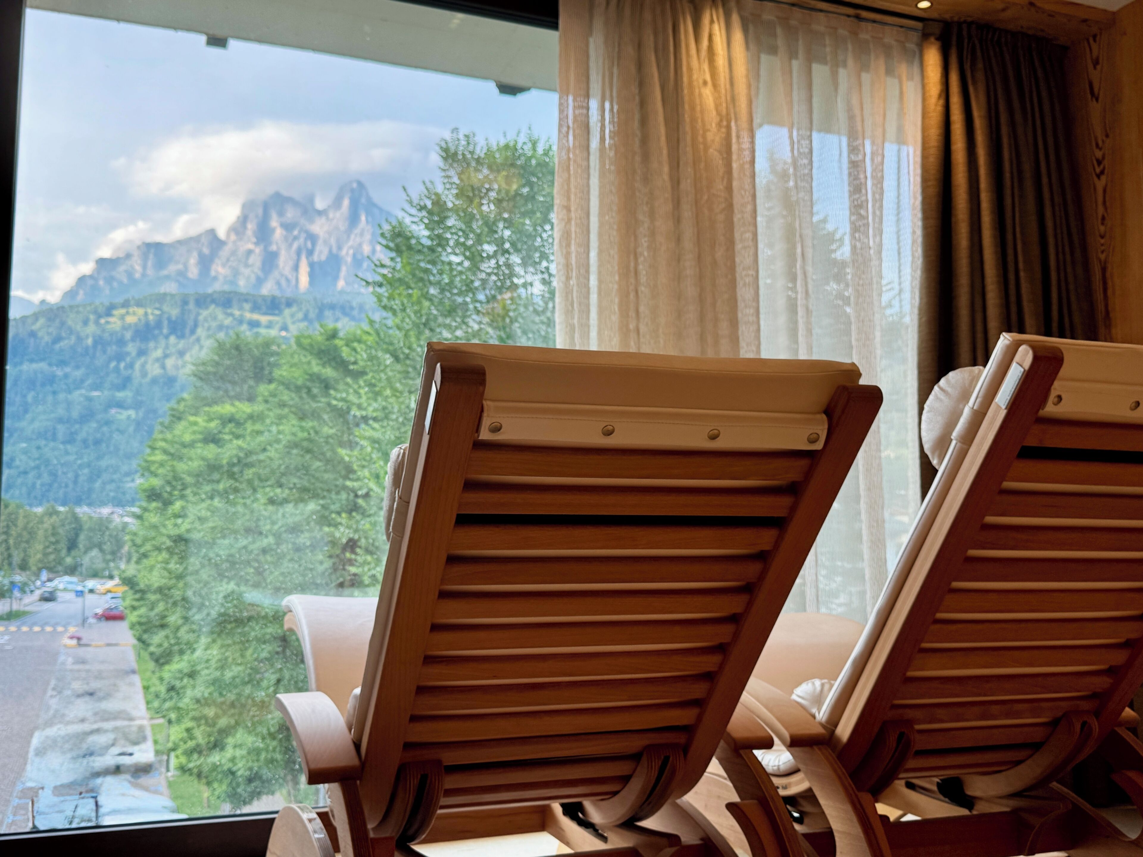 Deux fauteuils en bois, placés face à une fenêtre donnant sur une vue sur les montagnes.