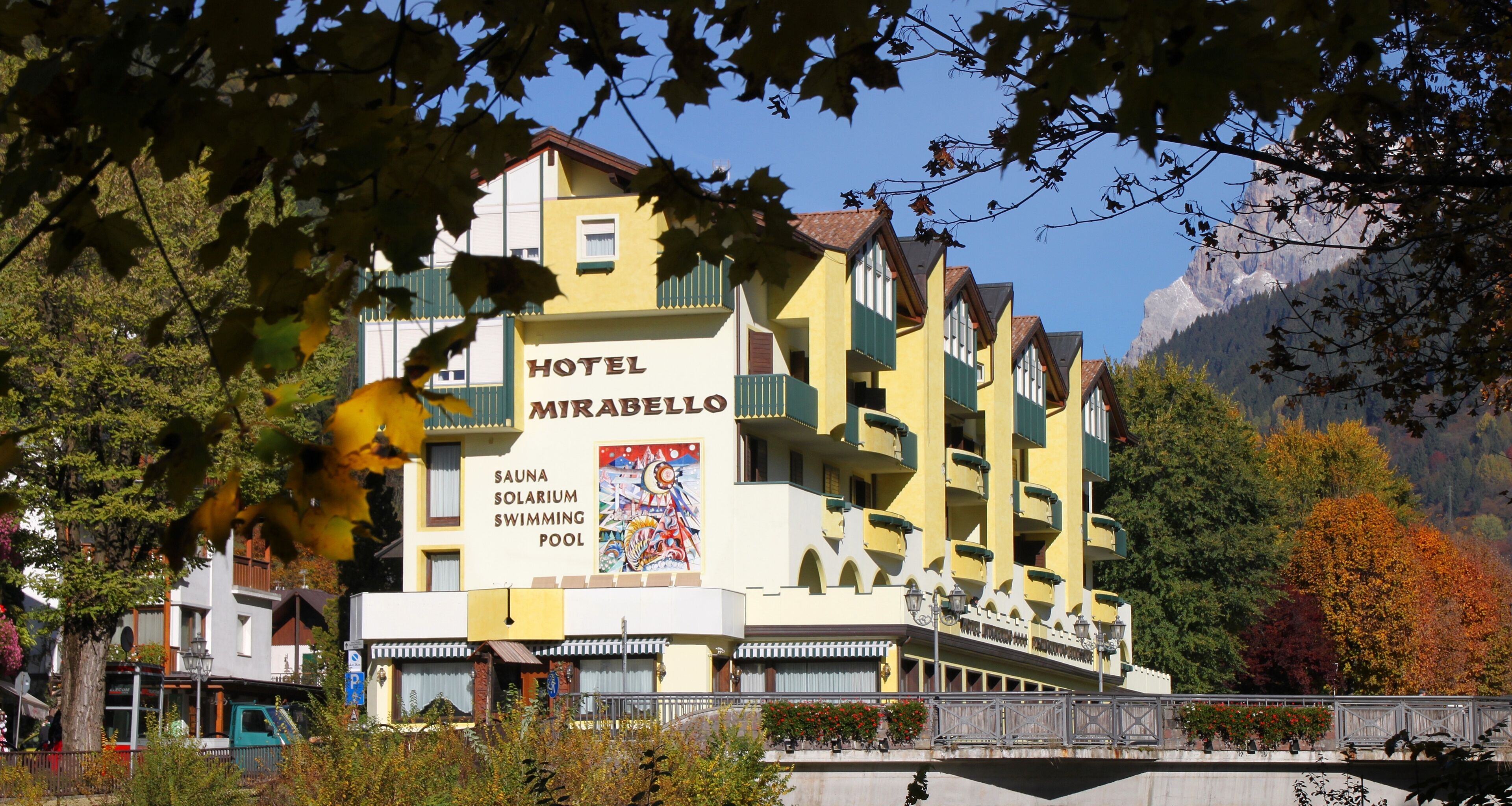 Ein mehrstöckiges Hotel namens MIRABELLO mit Schild für Sauna und Schwimmbad.