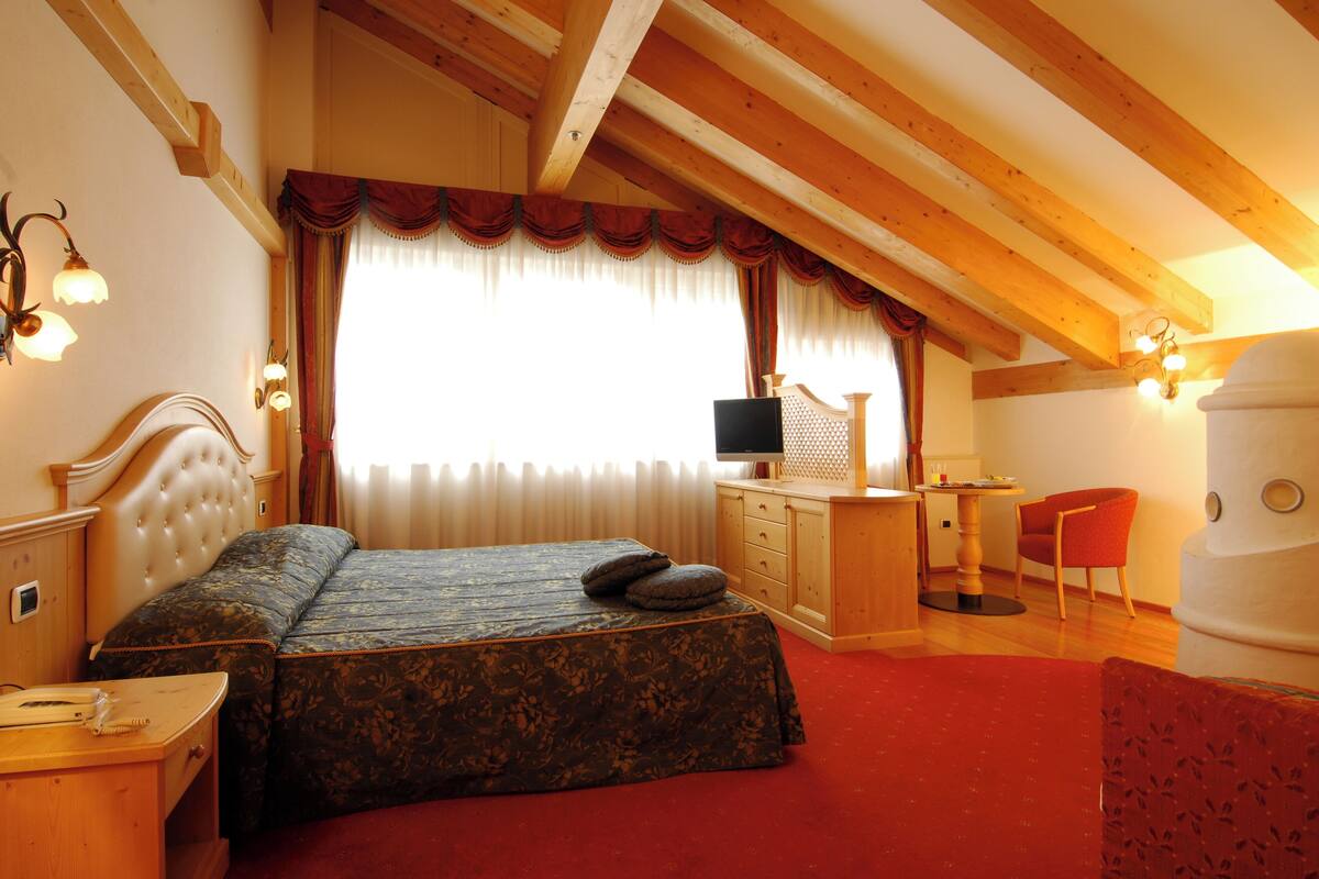 A bedroom with a large bed, a wooden desk, a chair, and a television.