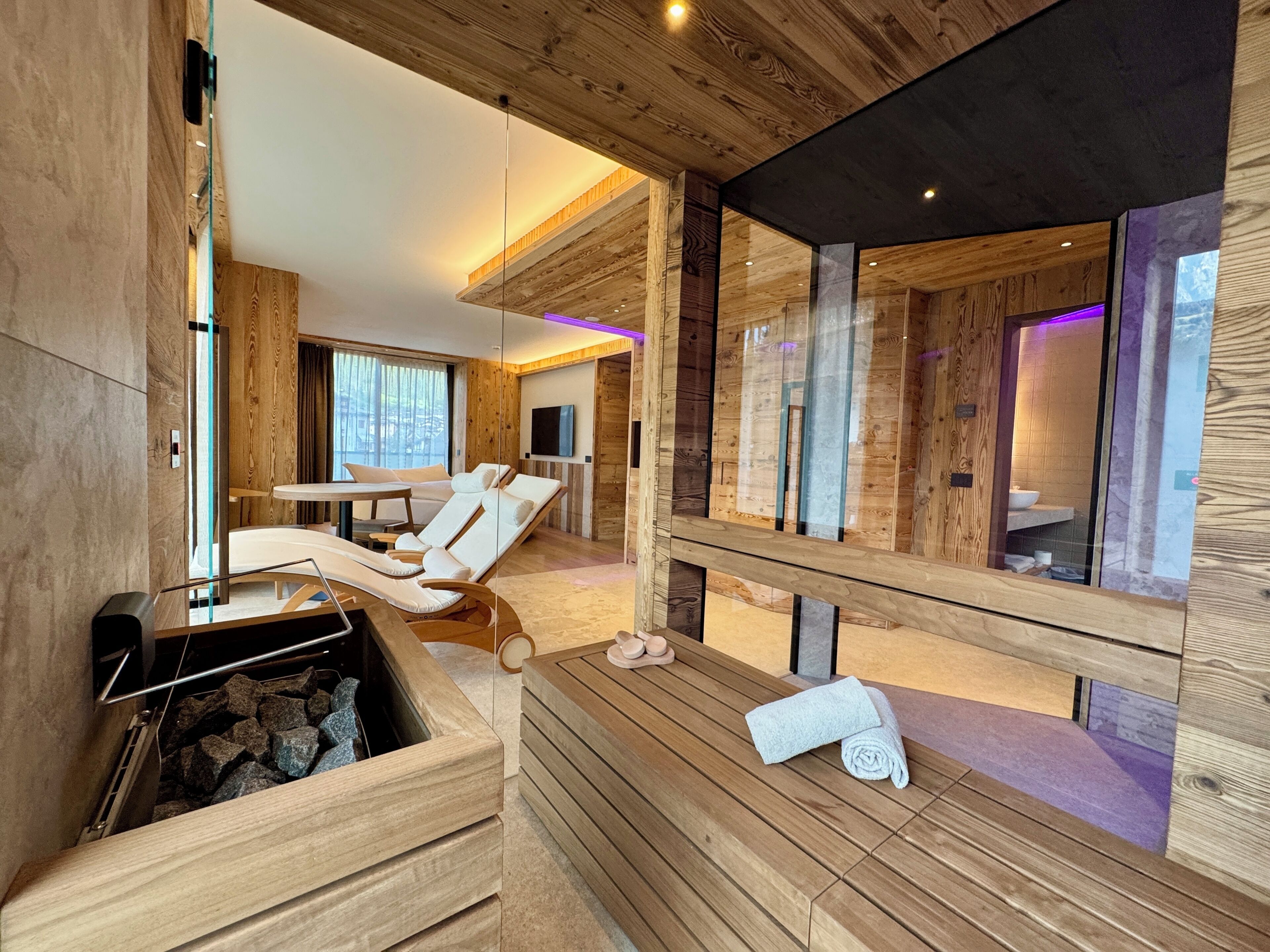 Une salle de spa moderne avec des murs en bois, un sauna et un espace de douche clos par des parois de verre.