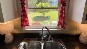 A kitchen with a window, a sink, and two lamps. - Parkers Flat 147, Comfy and Cozy.  Fully Furnished , Sparkling Clean . (Aiken)