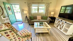 A living room with a sofa, a patterned armchair, a coffee table, a TV, and a bookshelf. - Parkers Flat 147, Comfy and Cozy.  Fully Furnished , Sparkling Clean . (Aiken)