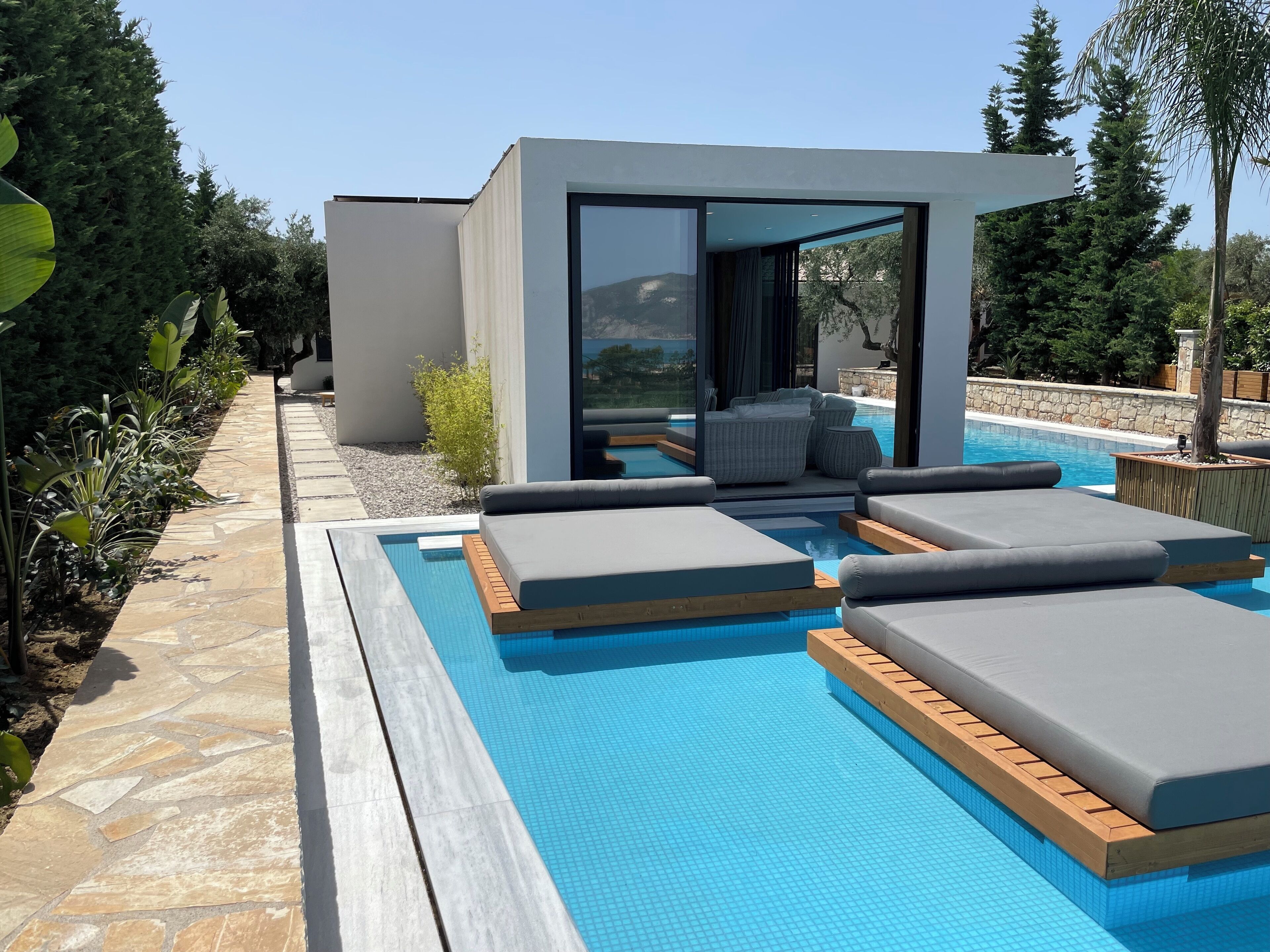 A modern outdoor pool area with built-in seating and a stone pathway.