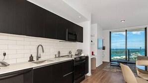 Una cocina moderna con armarios oscuros, encimeras blancas y un amplio ventanal con vistas panorámicas.