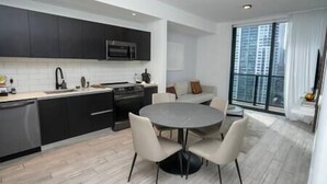 A modern kitchen with dark cabinets, a microwave, and a dining area with a round table and chairs. - Modern 3BR Oasis in Downtown Miami #1617 (Miami)