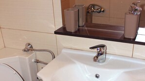 Une salle de bain avec un lavabo blanc, un miroir au-dessus et des toilettes à gauche.