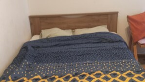 A bed with a wooden headboard, a blue and yellow patterned blanket, and white pillows. - Studio Sleeps 2 With Free Parking (Thessaloniki)