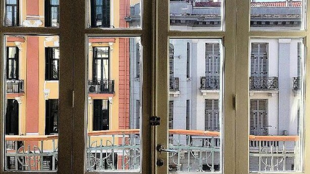 A door with multiple windows, each offering a view of adjacent buildings with balconies and railings. - Studio Sleeps 2 With Free Parking (Thessaloniki)