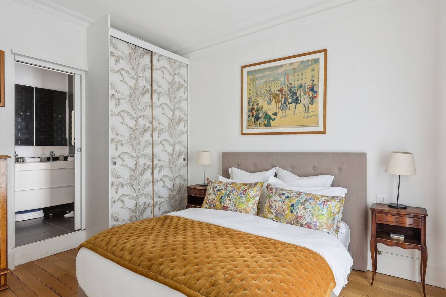 A hotel room with a bed, a nightstand, a lamp, a painting, and a wardrobe.